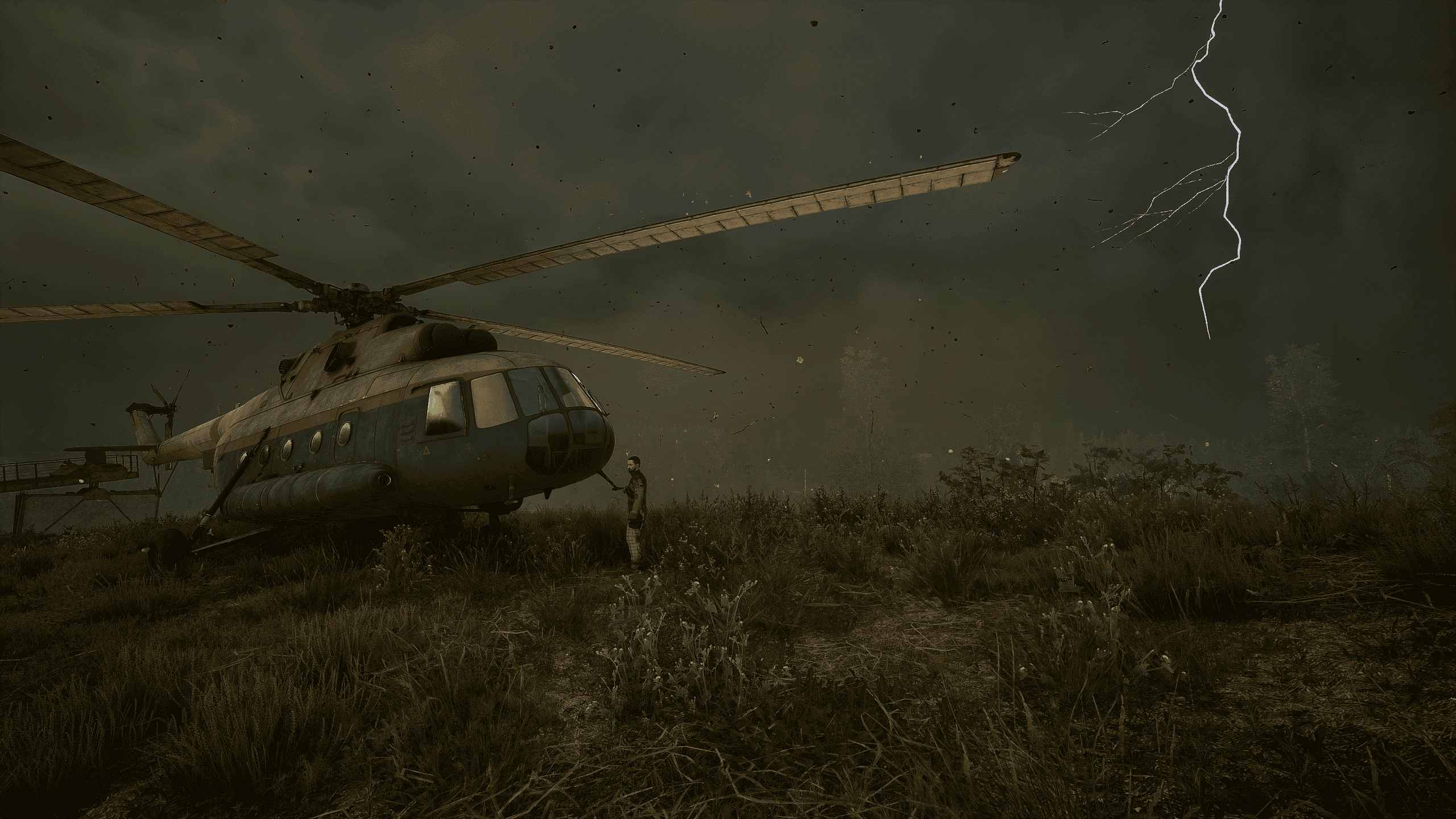 Ein Helikopter landet im Sturm – ein Blitz erhellt den bedrohlichen Himmel. Militärhubschrauber auf einer Wiese, daneben eine Person, im Hintergrund Blitze am dunklen Himmel.
